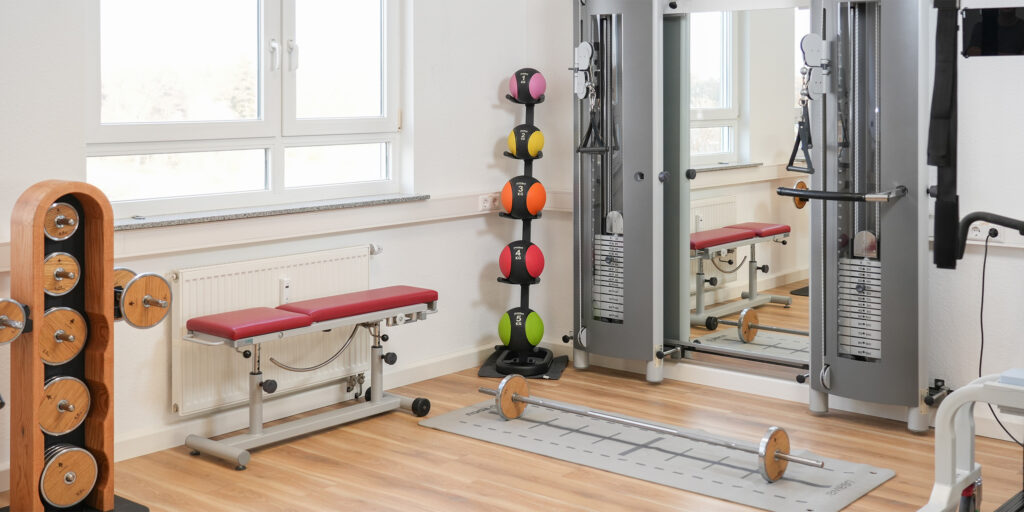 Moderner Fitnessraum mit Ger&auml;ten, Hanteln und Medizinb&auml;llen