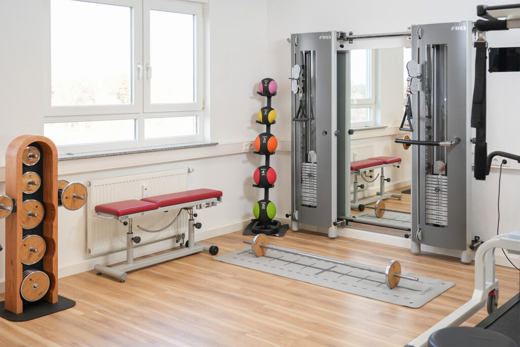 Moderner Fitnessraum mit Ger&auml;ten, Hanteln und Medizinb&auml;llen