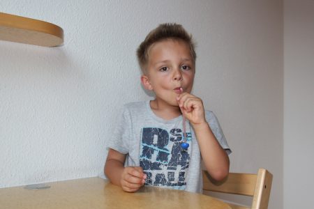 Junge &uuml;bt mit Strohhalm Gegestand anzuheben