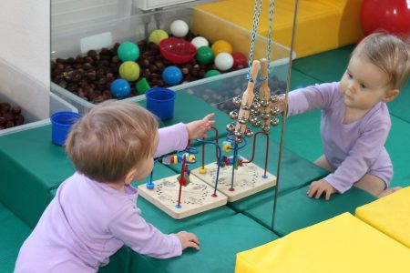 Baby spielt im Spiegelraum mit Holzspielzeug und bunten B&auml;llen